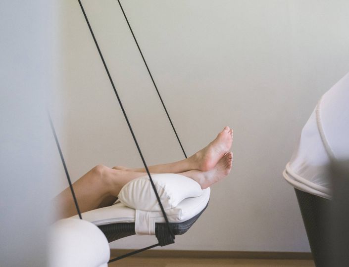 A person rests on a reclining lounger with legs raised in a quiet relaxation area.