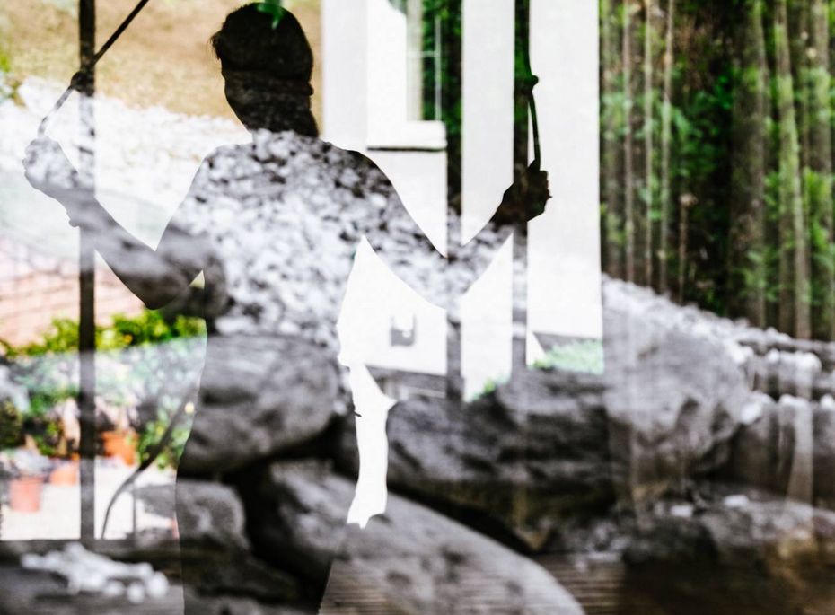 Saunabereich im Preidlhof mit Spiegelung Die Spiegelung einer sitzenden Person im Saunabereich ist hinter Glas und Pflanzen zu sehen.