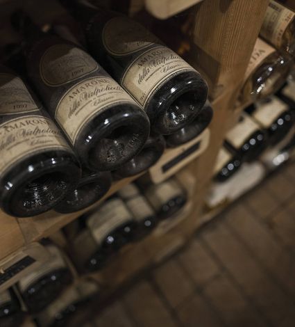 Le bottiglie di vino sono conservate su scaffali in legno in una cantina, riprese da vicino dall'alto.