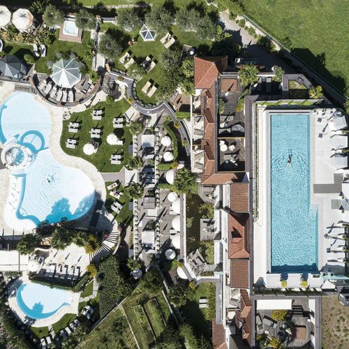 Luftaufnahme einer Poollandschaft mit mehreren Becken und Liegen im Preidlhof.