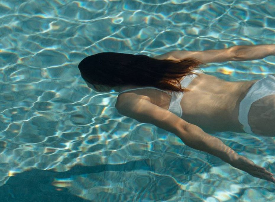 Wellnesspool mit schwimmender Frau im Preidlhof Eine Frau schwimmt im klaren Wellnesspool unter der Wasseroberfläche.