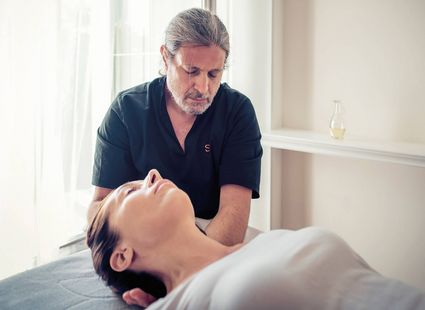 Un terapista esegue un trattamento wellness rilassante mentre una donna è sdraiata sul lettino.