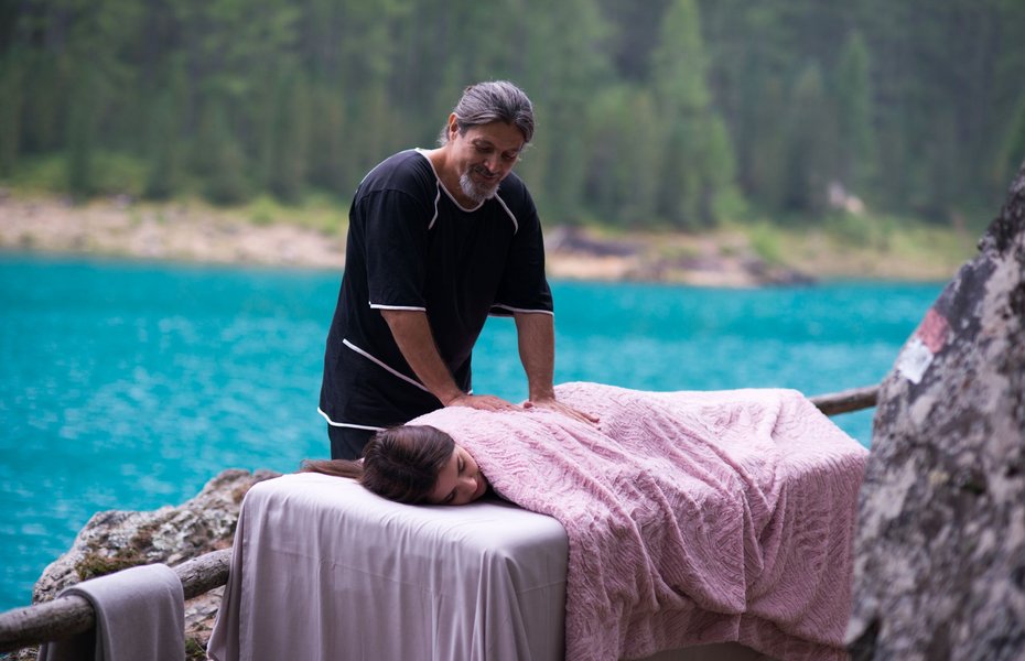 Ein Frau wird im Freien auf einer Massageliege massiert.