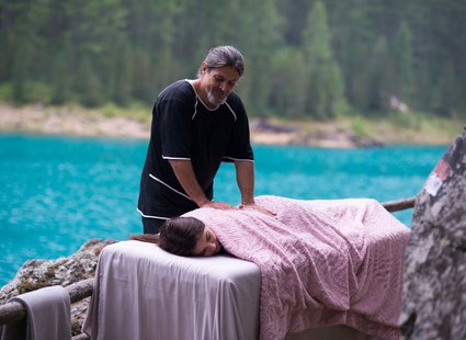 Ein Frau wird im Freien auf einer Massageliege massiert.