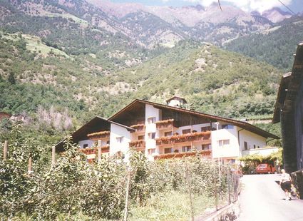 Ein familiengeführtes Hotel mit Balkonen und Holzgiebel vor den Bergen von Naturns.