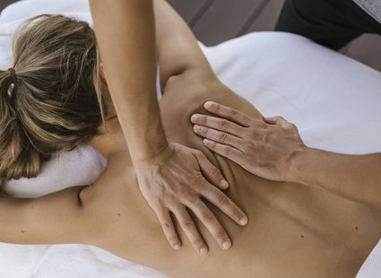 Eine Person erhält eine Rückenmassage auf einer Liege im Wellnessbereich.