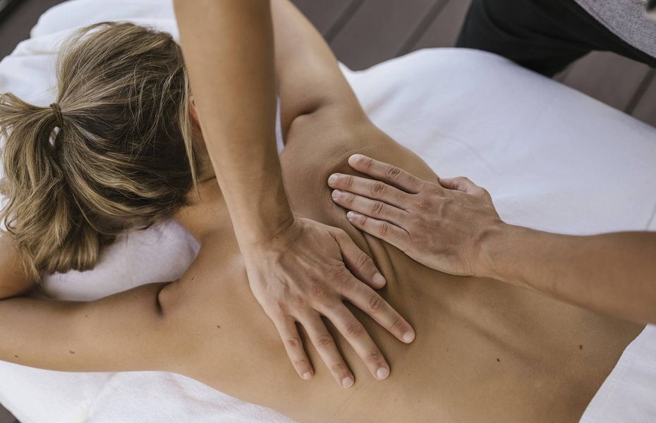 Massage im Wellnesshotel in Naturns Eine Person erhält eine Rückenmassage auf einer Liege im Wellnessbereich.