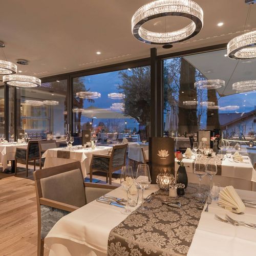 Elegant gedeckte Tische im Gourmetrestaurant mit großen Fenstern und Blick ins Abendlicht.