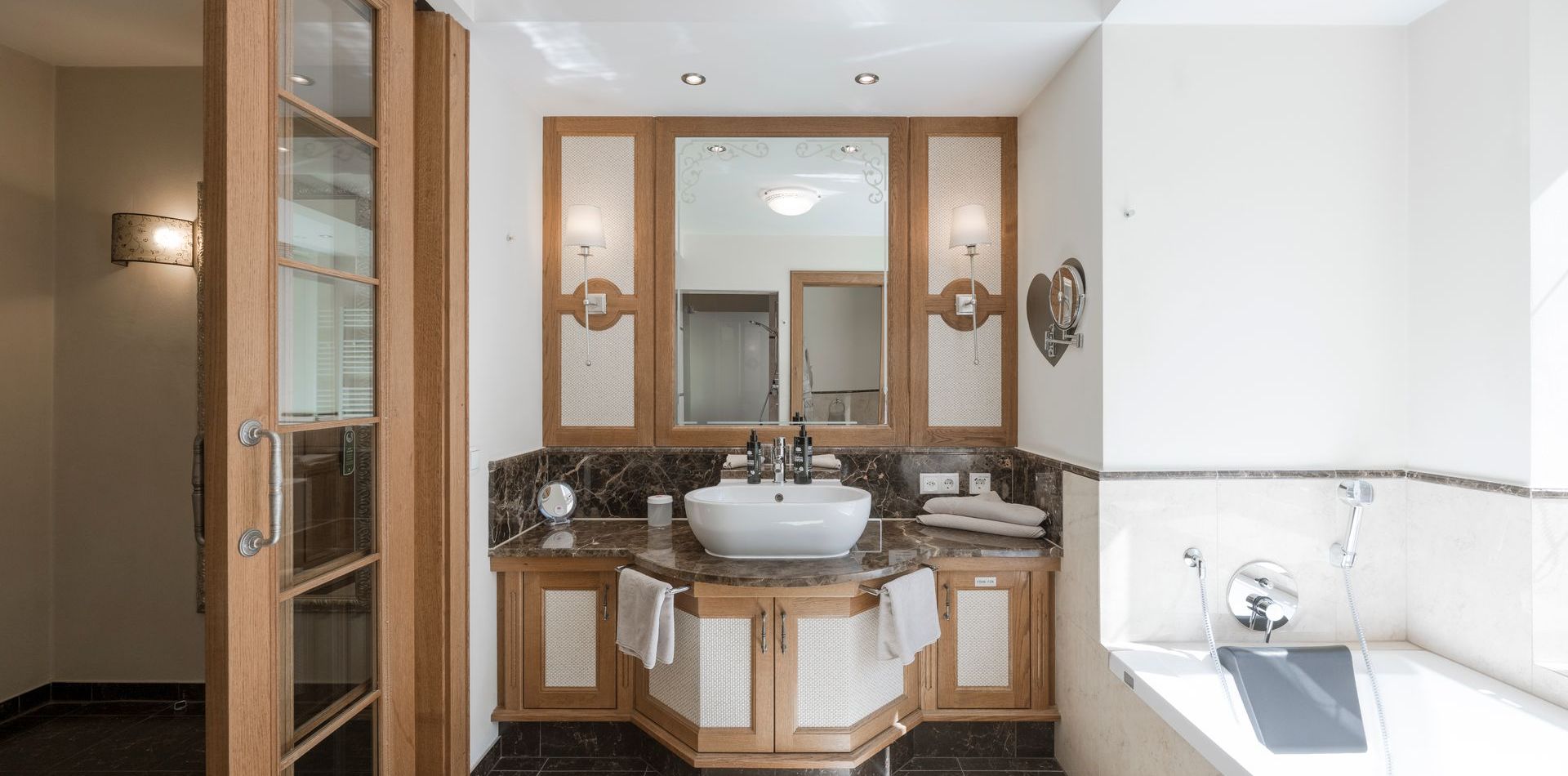 Ein helles Badezimmer mit Doppelwaschtisch, Badewanne und Holzdetails in der Luxury Suite Magnolie.
