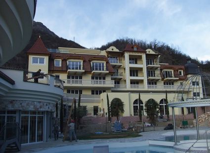 Das Hotelgebäude des Preidlhof steht vor einem Berghang, davor ist der Poolbereich zu sehen.