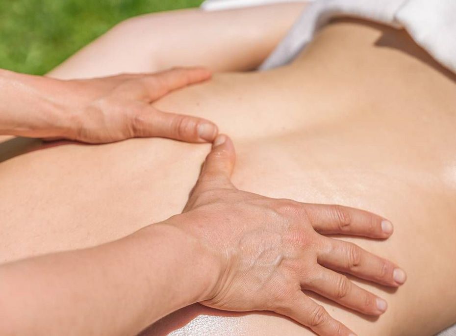 Massage im Wellnesshotel in Naturns Hände massieren den Rücken einer liegenden Person im Freien auf einer Liege.