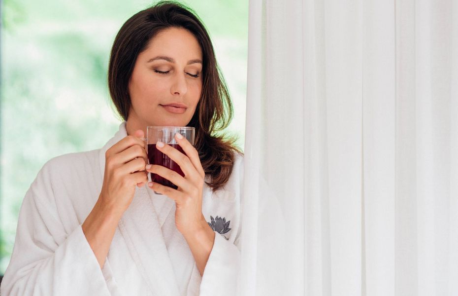 Wellnesshotel in Naturns: Tee im Bademantel Eine Frau im Bademantel hält in einem Wellnesshotel eine Tasse Tee und hat die Augen geschlossen.