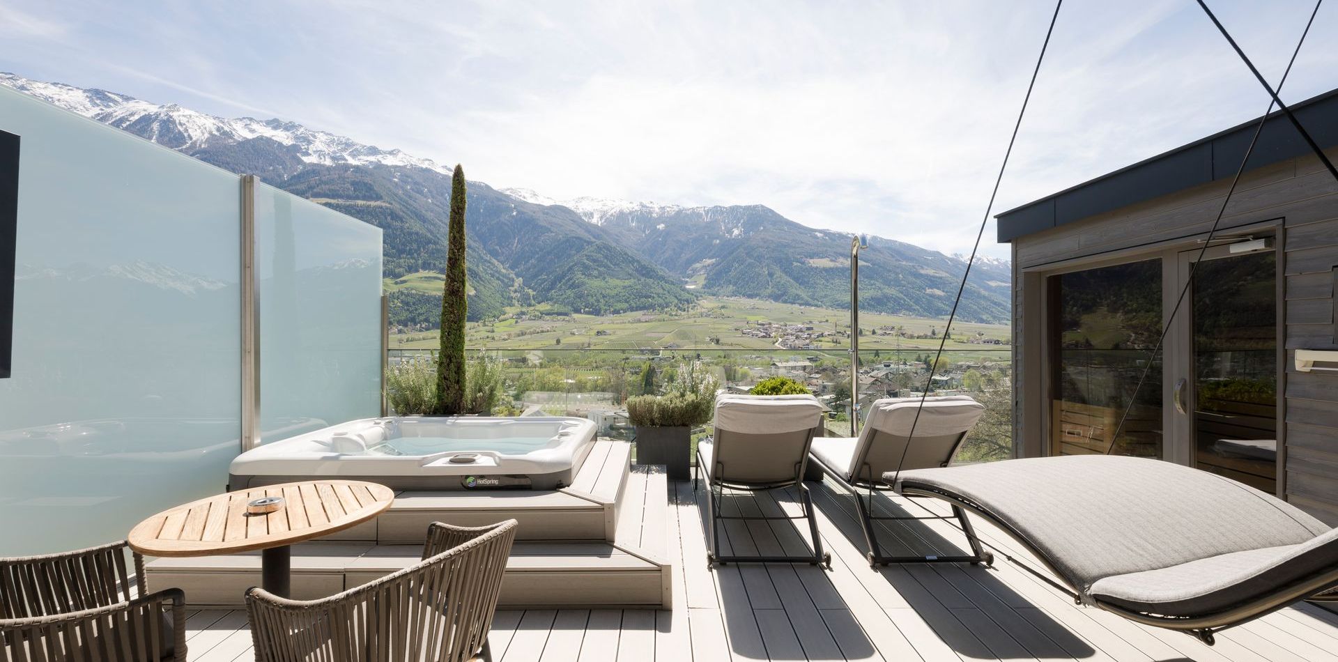 Die Dachterrasse der Penthouse Suite DolceVita mit Whirlpool, Liegen und Blick auf die Berge.