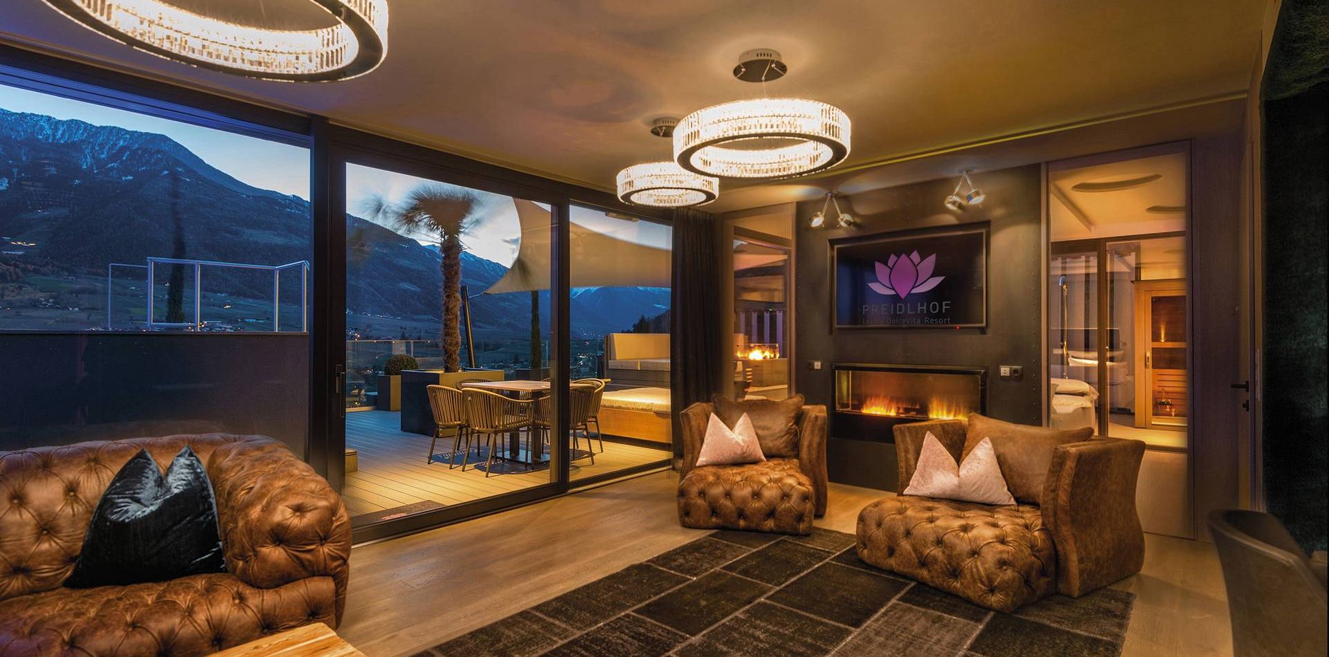 Una raffinata penthouse suite con divani in pelle, luci moderne e terrazza con vista montagna al Preidlhof.