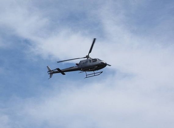 Un elicottero vola contro un cielo azzurro e nuvoloso.