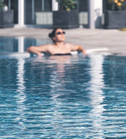 Una donna si rilassa nella piscina wellness all'aperto con le braccia appoggiate al bordo.