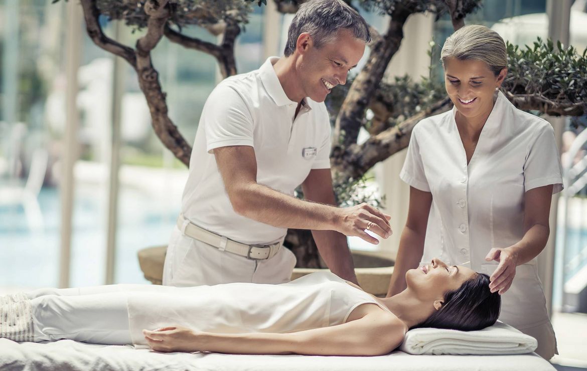 Due terapisti eseguono un trattamento medical spa su una donna sdraiata su un lettino da massaggio.