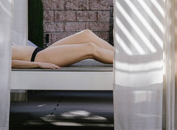 A person lies on a spa relaxation lounger behind sheer curtains.