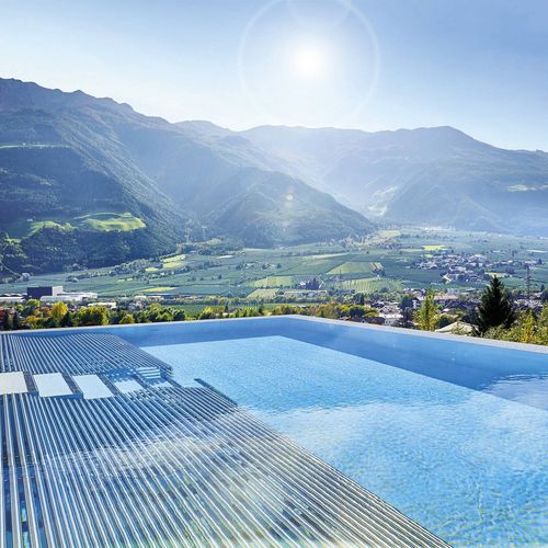 Ein Infinity Pool mit Sonnendeck blickt über das Tal und die Berge im Hintergrund.