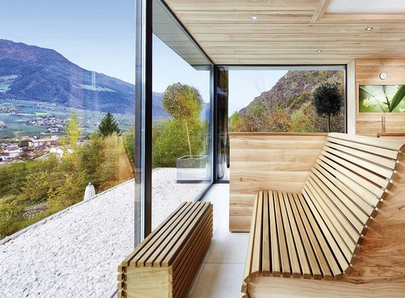 Una sauna in legno con parete vetrata si affaccia sulla valle e sulle montagne.