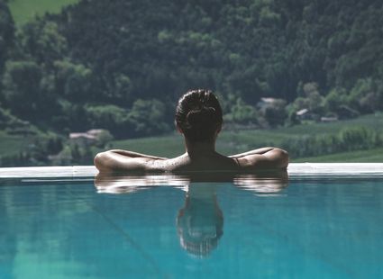 Una persona si rilassa in una piscina a sfioro con le montagne sullo sfondo.