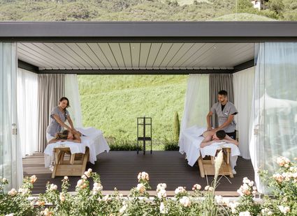 Zwei Massageliegen im offenen Pavillon mit Blick auf die grüne Hügellandschaft.