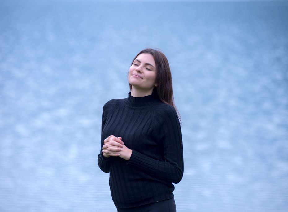 Eine Frau mit geschlossenem Blick steht entspannt vor dem Wasserbecken im Wellnesshotel.