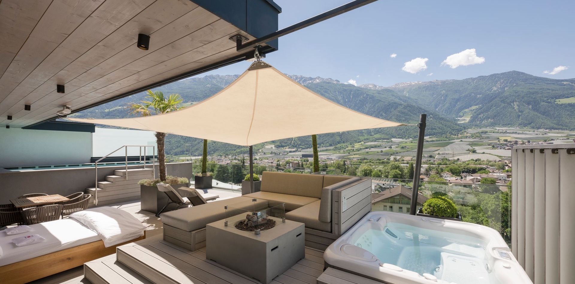 Eine private Dachterrasse der Penthouse Suite mit Lounge-Möbeln, Sonnensegel und Whirlpool mit Bergblick.