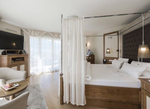 Eine helle Luxury Suite mit Himmelbett, Sitzbereich und großen Fenstern im Preidlhof in Naturns.
