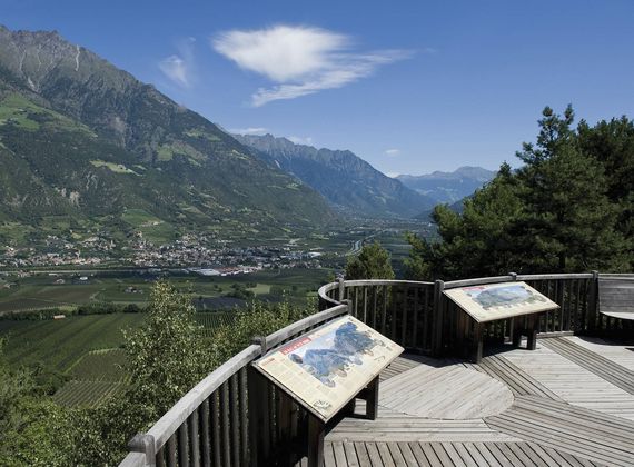 Ein Holz-Aussichtspunkt mit Infotafeln überblickt das Tal und die Berge im Vinschgau.