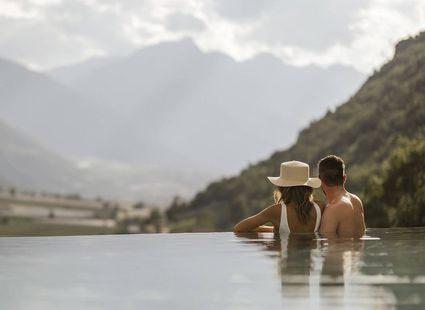 Una coppia si rilassa nella piscina a sfioro mentre guarda il paesaggio montano.
