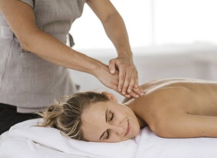 Una terapista massaggia la schiena di una donna distesa a pancia in giù sul lettino.
