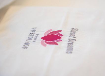 Weiße Bettwäsche mit pinkem Preidlhof-Logo und dem Schriftzug Sweet Dreams.