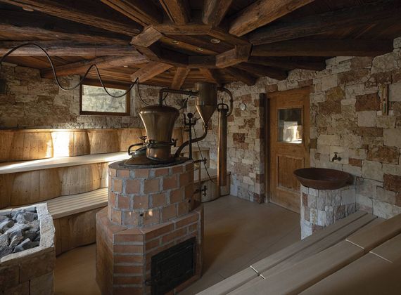 Eine rustikale Sauna mit Holzbänken, Natursteinwänden und einem Ofen im Sauna Tower.