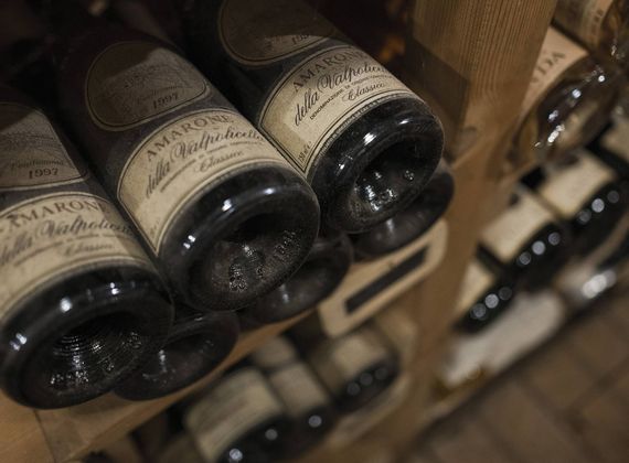Mehrere Amarone-Flaschen liegen waagerecht in einem Weinregal mit Holzfächern.