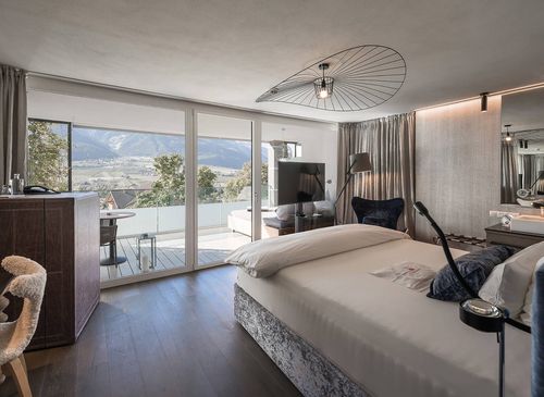 Ein modern eingerichtetes Schlafzimmer mit Balkon und Blick auf die Berge im Preidlhof.