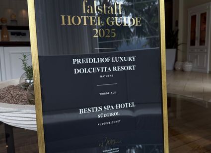Ein gerahmtes Schild zeigt Auszeichnungen des Preidlhof Luxury DolceVita Resort im Falstaff Hotel Guide 2025.