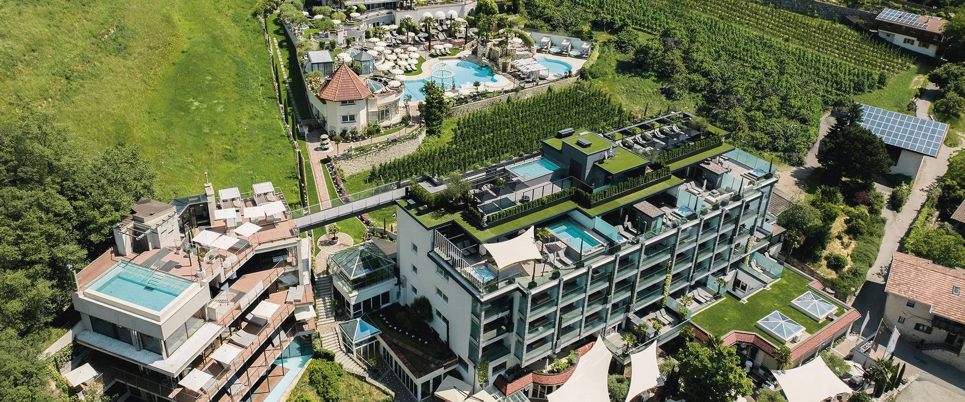 Aerial view of a wellness hotel with outdoor pools, terraces and gardens set among vineyards.