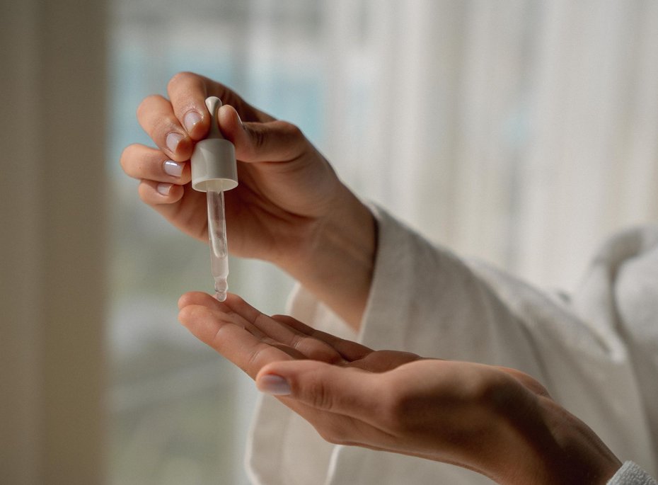 Eine Hand die mit einer Pipette Pflegeöl aufträgt.