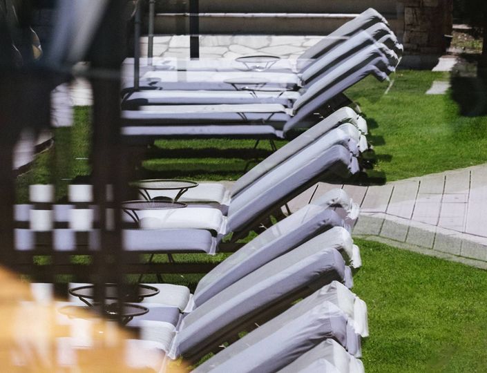 Rows of reclining loungers stand on the grass beside a paved path in the outdoor relaxation area.