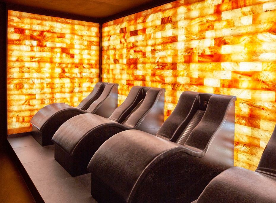 Salzraum mit Liegen im Wellnesshotel Preidlhof Im Salzraum stehen mehrere geschwungene Liegen vor warm leuchtenden Salzsteinwänden.