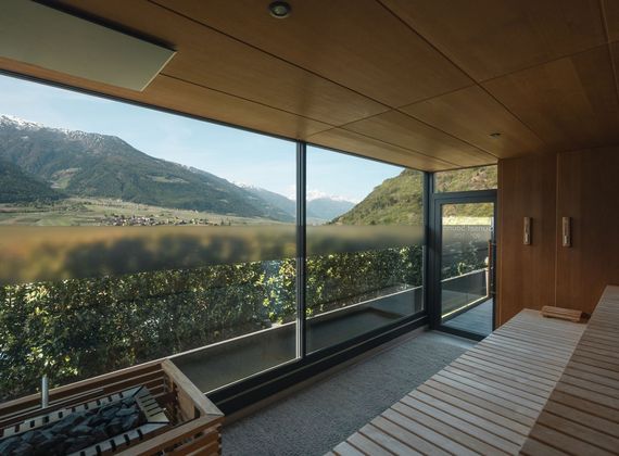 Blick aus dem Saunabereich durch große Fenster auf die Berge und das Tal.
