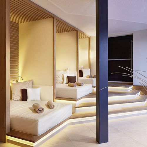 Eine stilvolle Wellnesssuite mit zwei Betten, Holzdetails und indirekter Beleuchtung im Preidlhof.