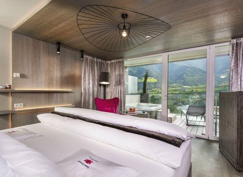 Luxury Suite Bedroom at Preidlhof in Naturno A modern suite bedroom with twin beds, a small balcony, and mountain views through glass doors.