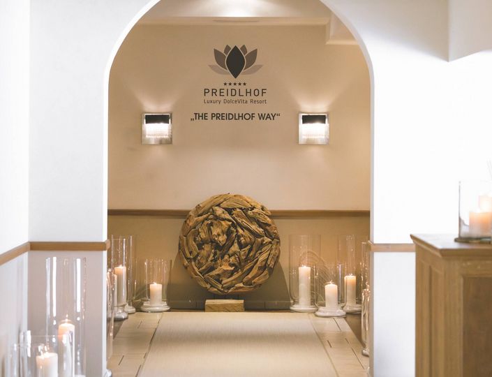Un corridoio illuminato da candele al Preidlhof con una sfera decorativa intrecciata e pareti beige.