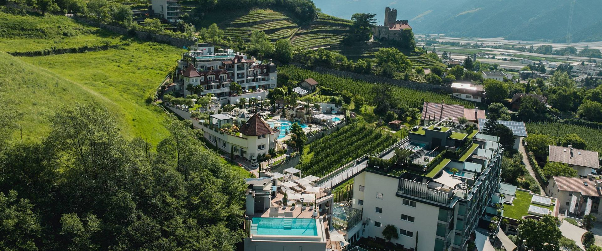 Luftaufnahme des Adults Only Wellnesshotels Preidlhof mit Pools und Terrassen am Hang in Naturns.