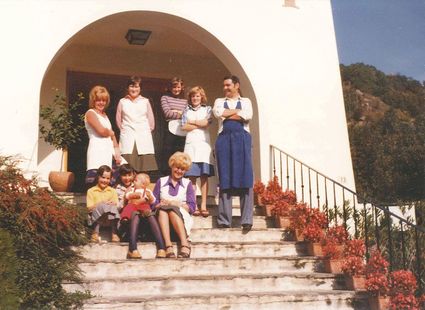 Sechs Mitglieder der Familie Ladurner stehen und sitzen vor dem Eingang des Preidlhofs auf einer Treppe.