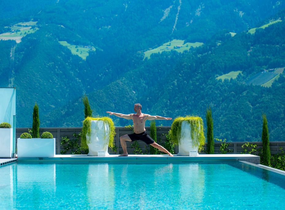 Infinity-Pool im Preidlhof mit Bergblick Ein Mann übt Yoga am Rand des Infinity-Pools mit Blick auf die Berge.