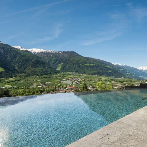 Der Infinity Pool liegt vor einer Bergkulisse mit Blick über das Tal und den klaren Himmel.