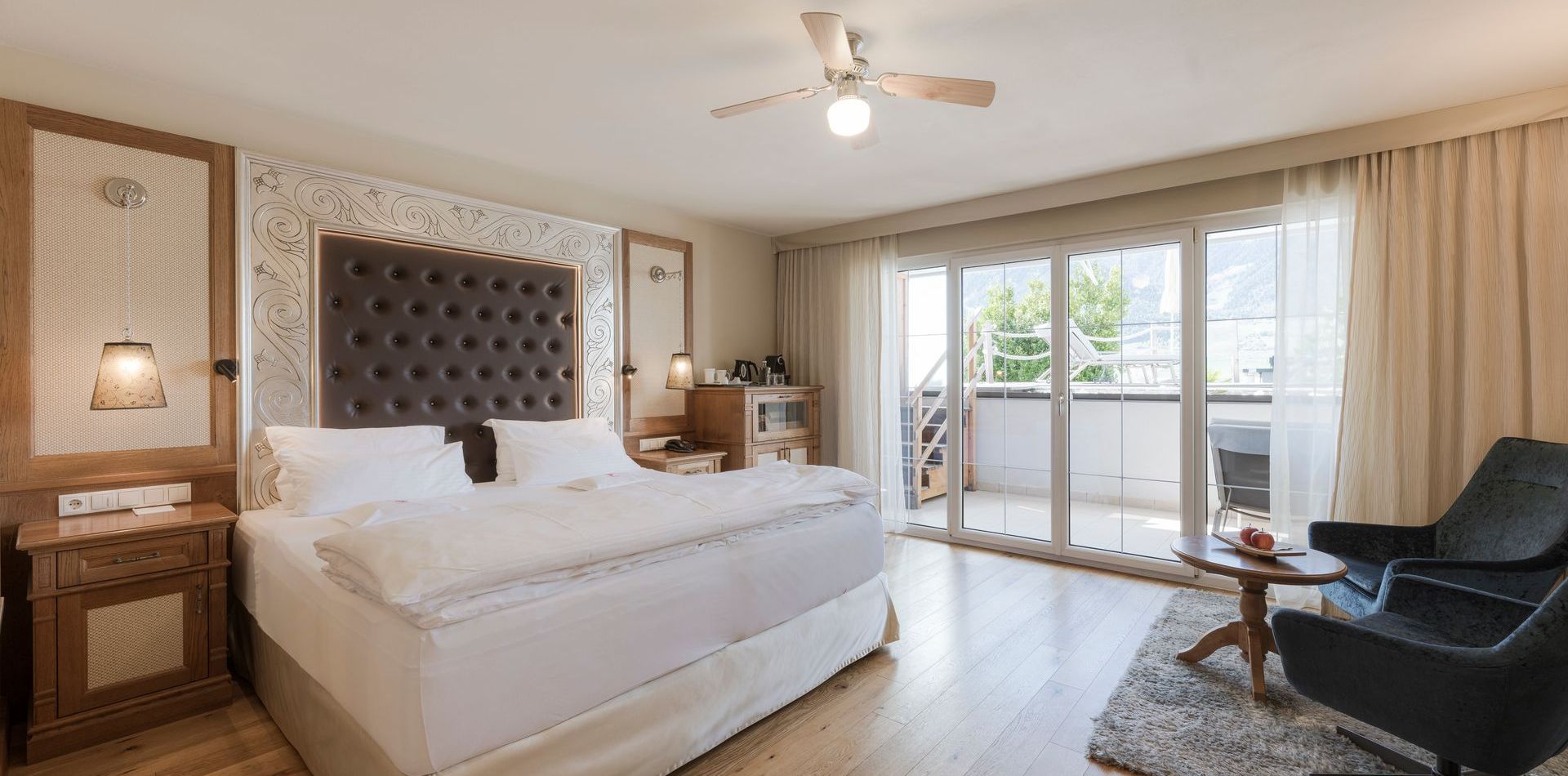 Helles Schlafzimmer der Luxury Suite Lantana mit großem Bett, Sitzbereich und Zugang zum Balkon.